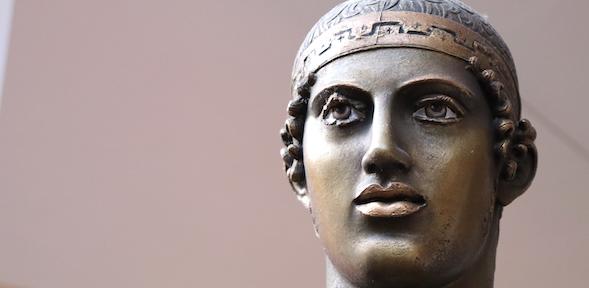 Bronze face of Delphi chariotteer with painted eyes and copper lips